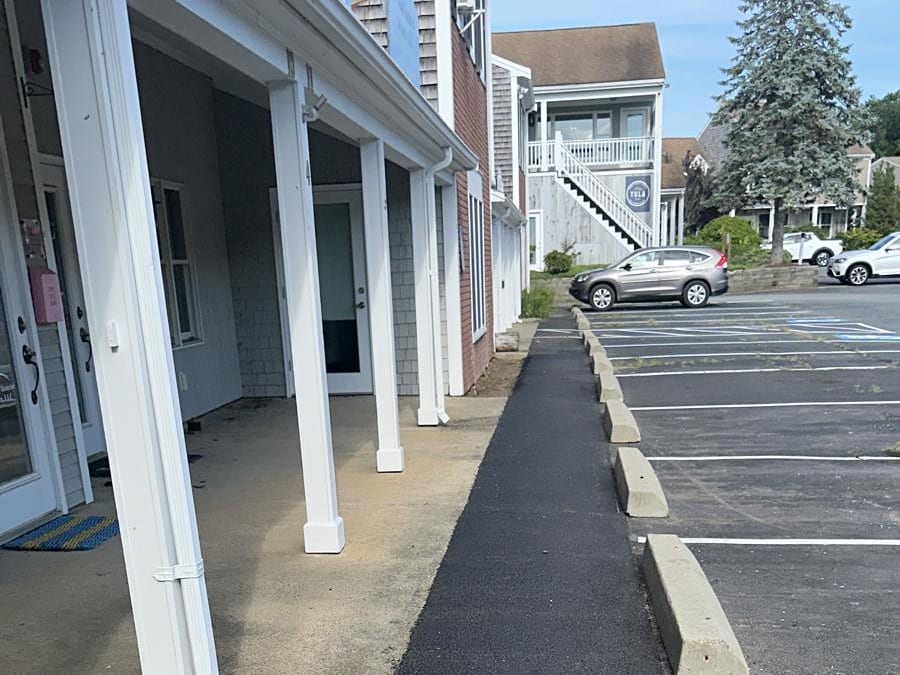 Fresh asphalt walkway repair along a commercial building