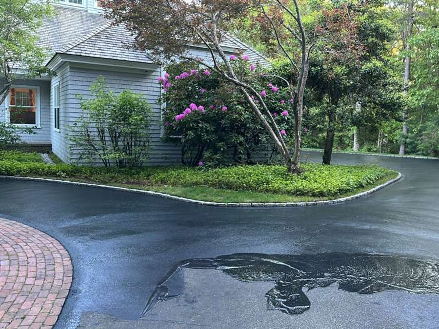 Curved residential driveway with fresh dark sealcoating around landscaping