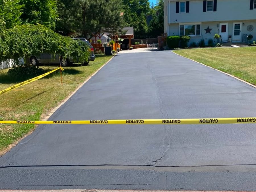 Long residential driveway freshly sealed on a sunny day