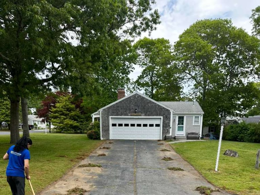 Worker cleaning and preparing a driveway before sealcoating